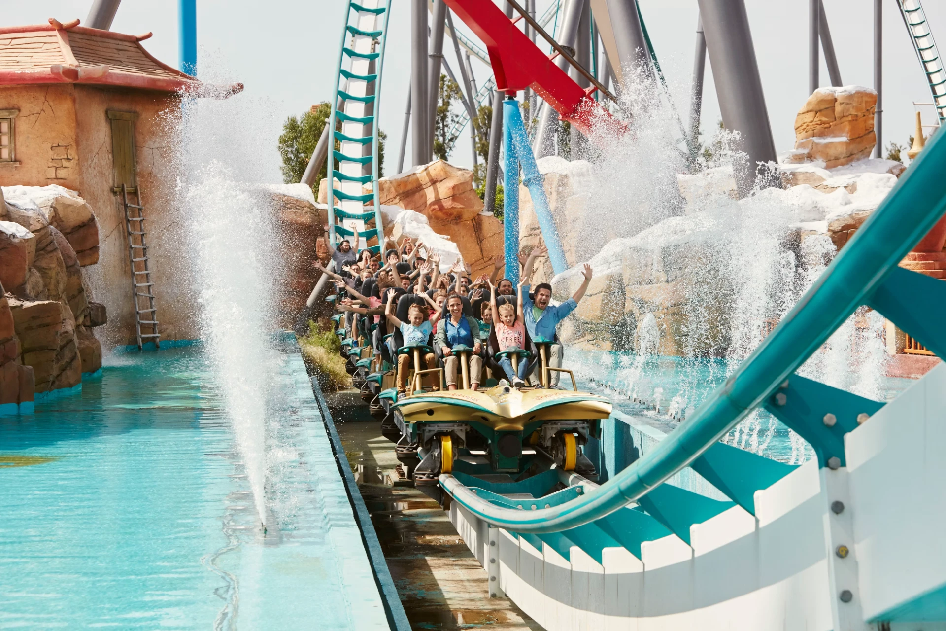 Grupo de visitantes de braços no ar numa atração aquática do PortAventura World, entre cortinas de água