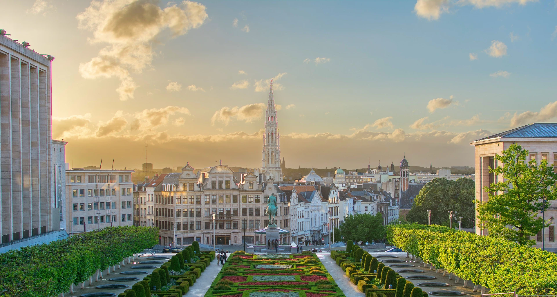 Jardins do Mont des Arts ao pôr do sol, com a torre da Câmara Municipal ao fundo