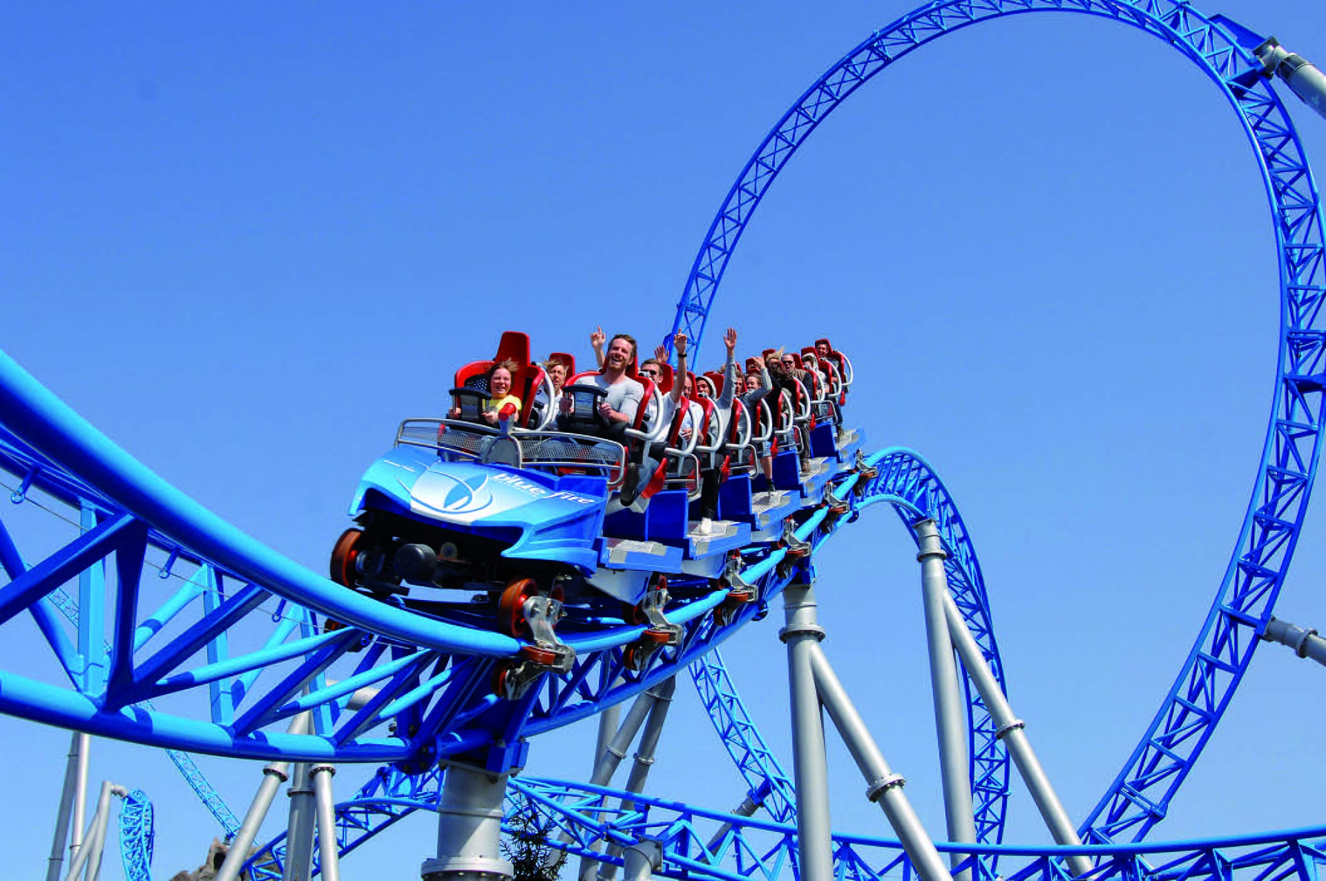 Comboio azul da Blue Fire em curva com o loop da montanha-russa ao fundo