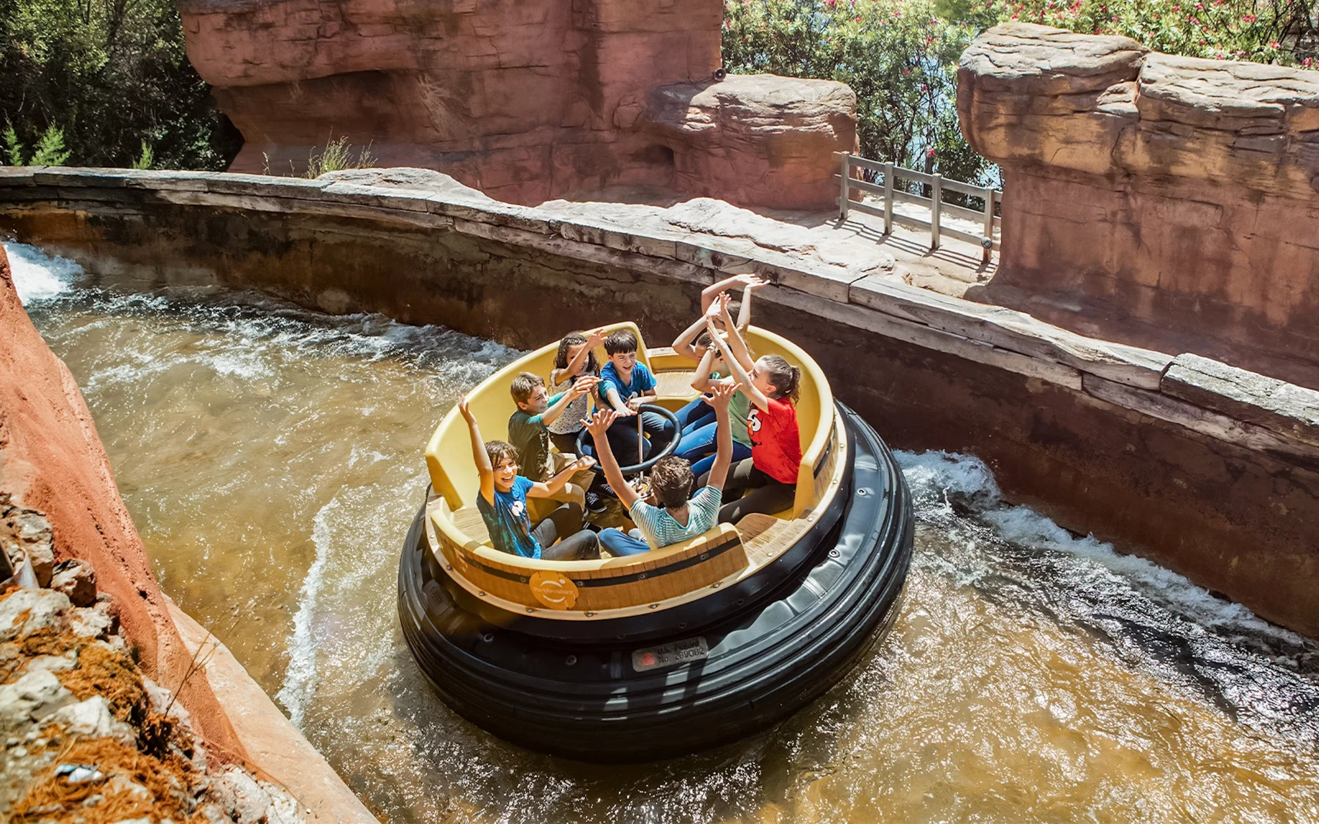 Jovens num barco circular a descer os rápidos do PortAventura World entre paredes de rocha